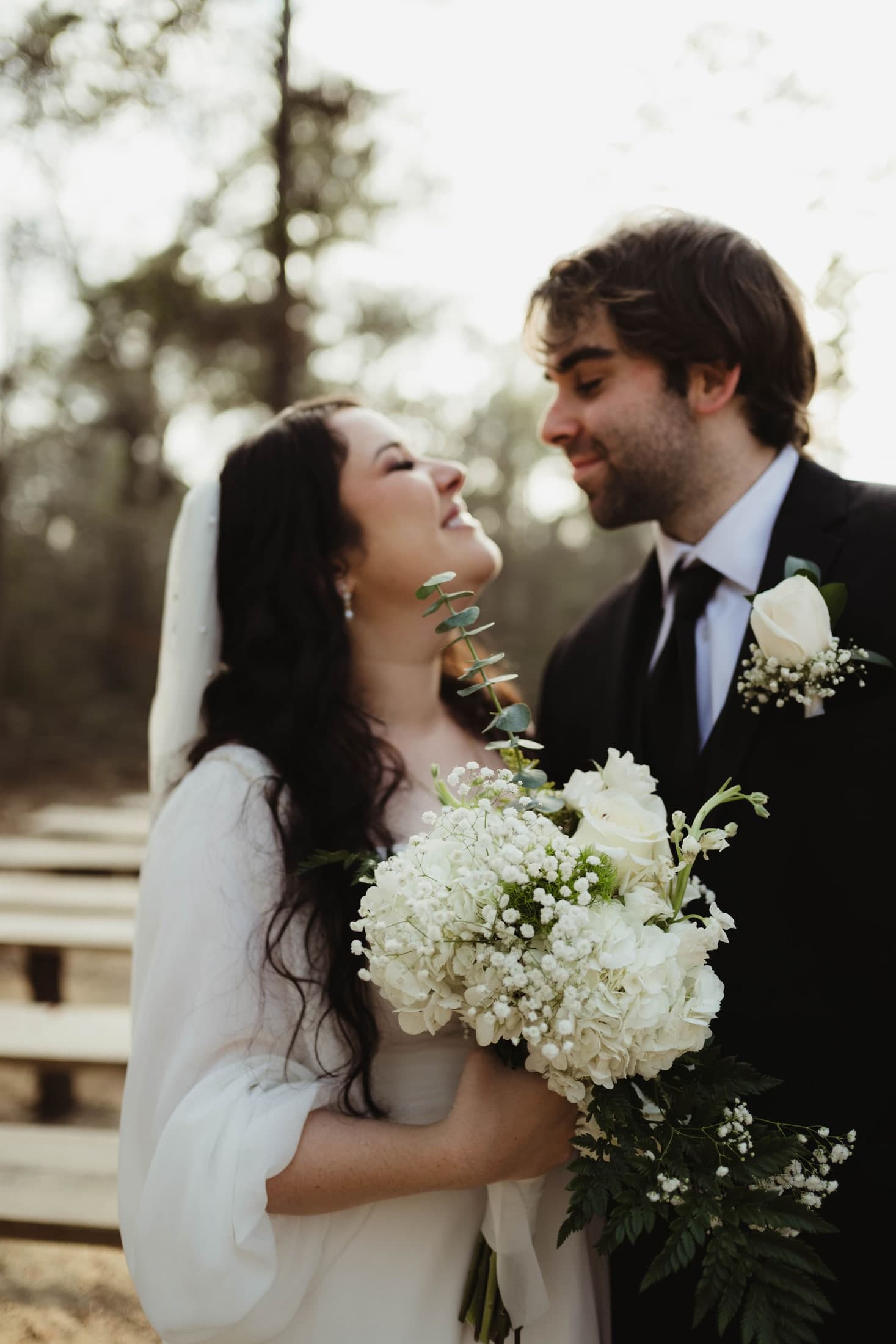 Katie smiling up at Ben while holding her white bridal bouquet