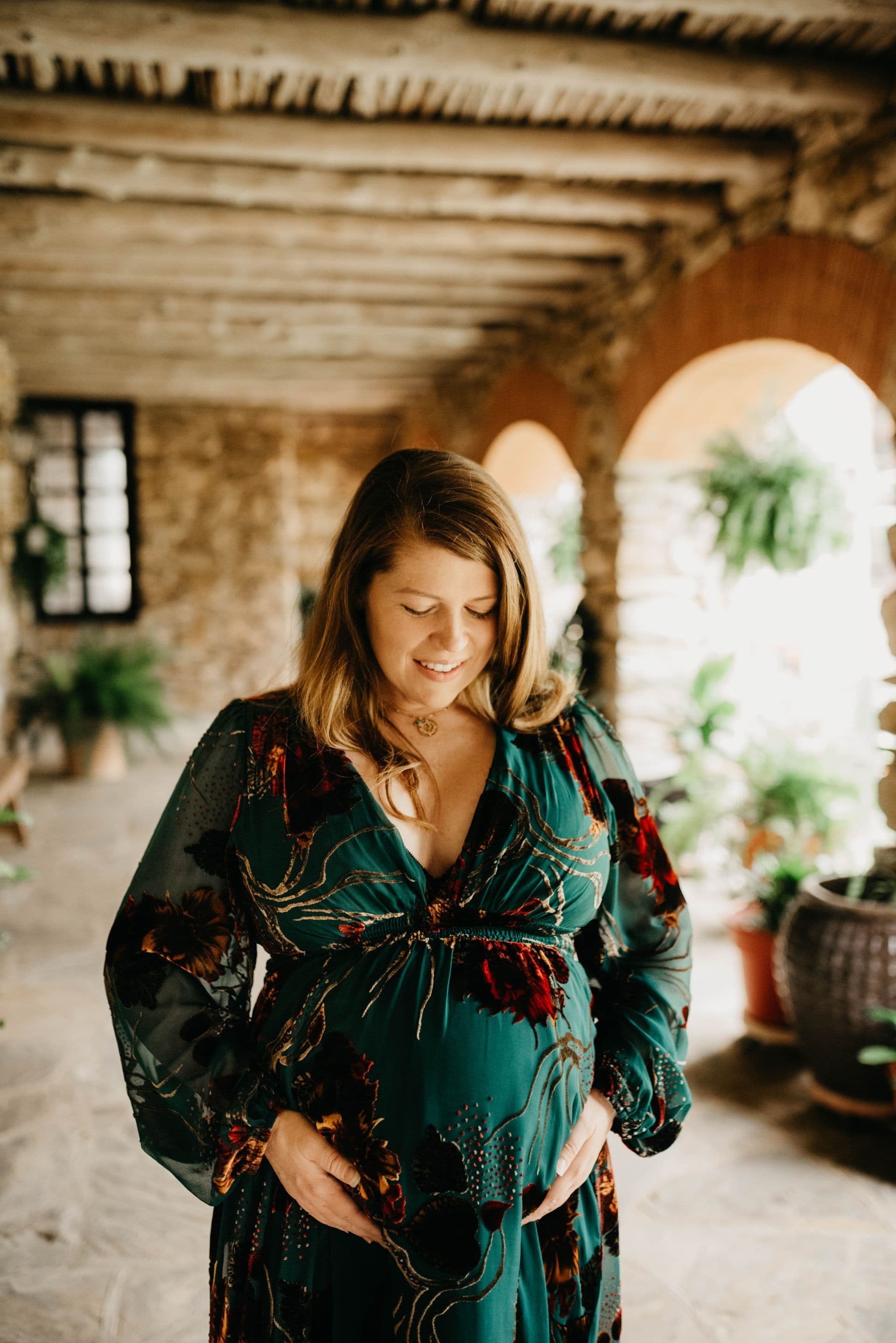 An expectant mother in a green dress during a San Antonio maternity portrait session