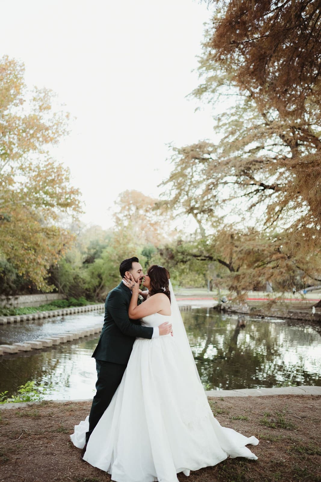 Andres and Sam together beside a still pond framed by autumn trees