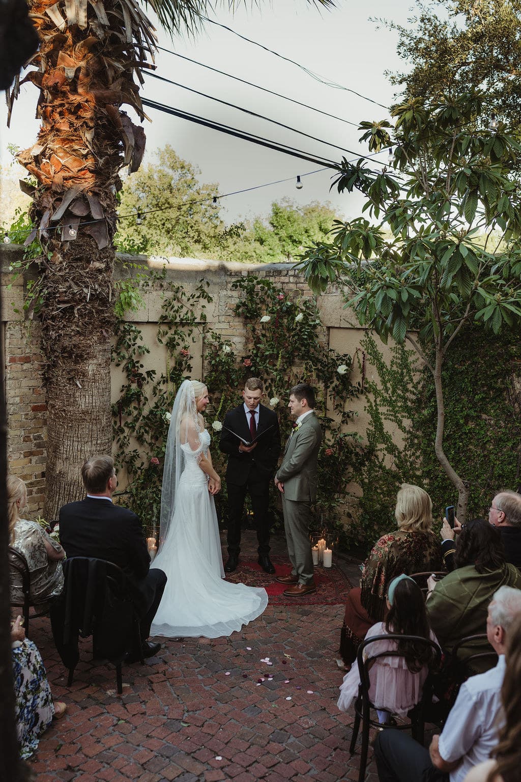 Ben and Elizabeth face one another beneath a palm tree during their courtyard ceremony.