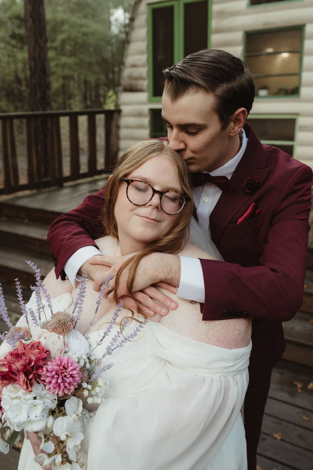 Chad embracing Jessica on the cabin deck as she rests against him