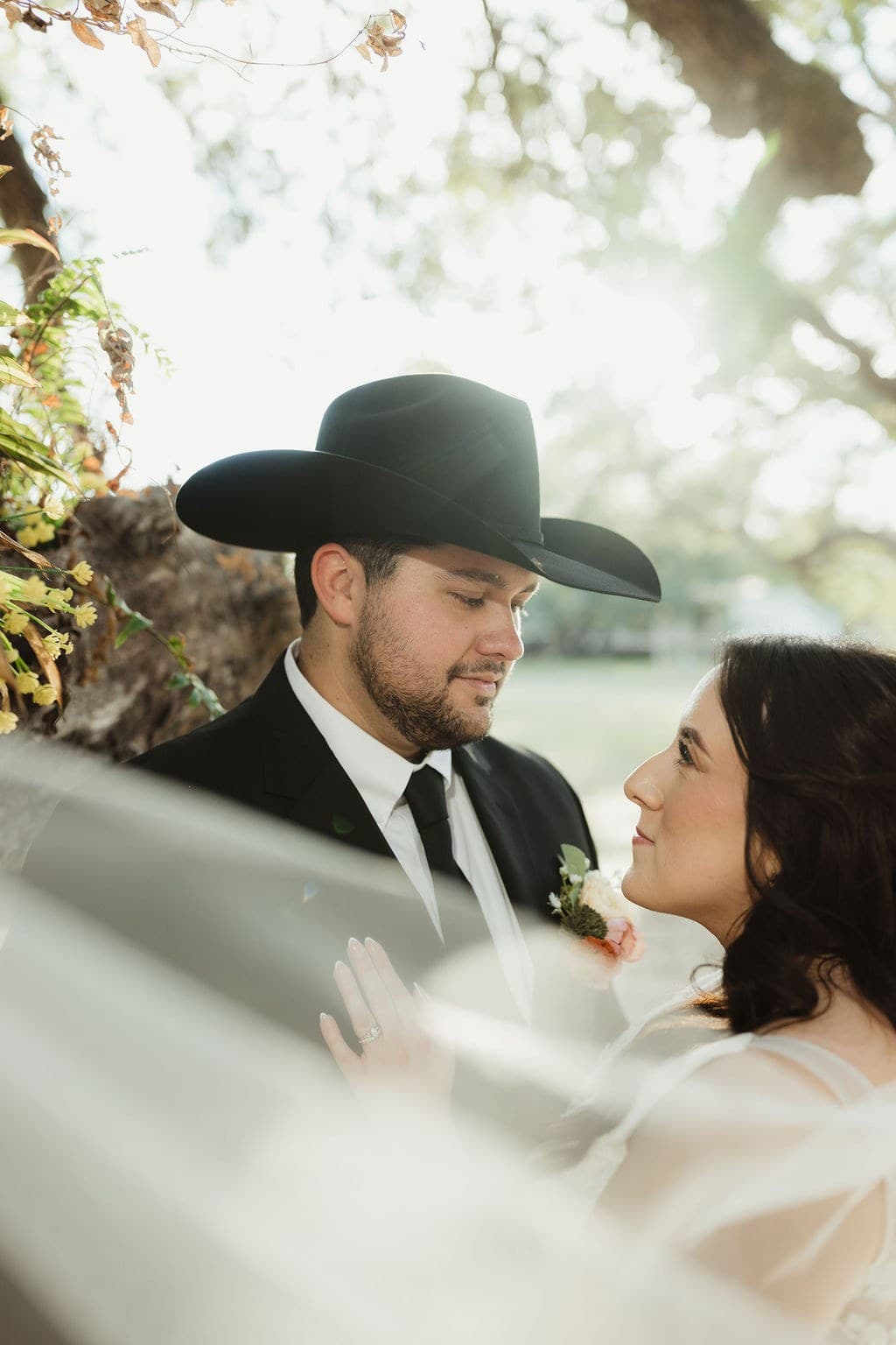 Nick and Savannah smiling at each other beneath her veil in soft outdoor light